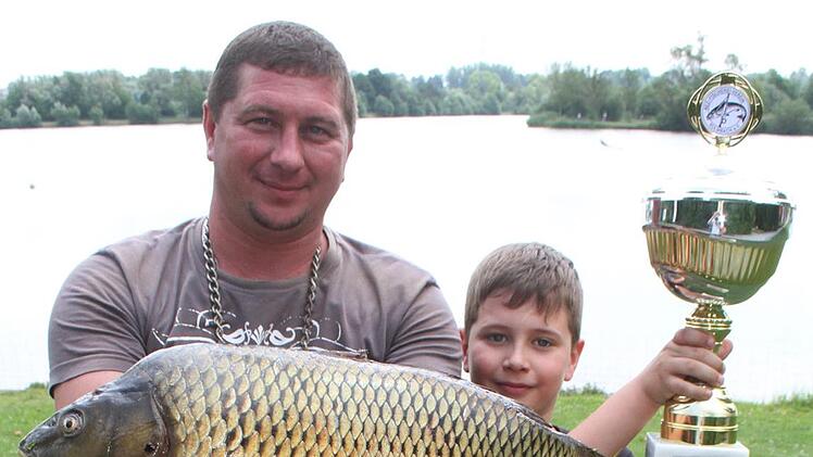 Alexander Shuldays ist zum ersten Mal Fischerkönig geworden und freute sich riesig. "Der Karpfen wird noch heute gemacht", sagt der passionierte Angler. Sohn Viktor (9) nimmt sich Papa als Vorbild. Foto: Sonny Adam