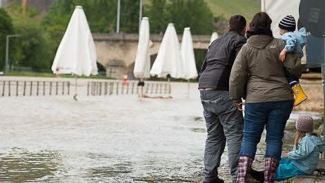 Eine Familie schaut sich am Sonntag das Hochwasser am Main in Würzburg an. Foto: Tobias Köpplinger