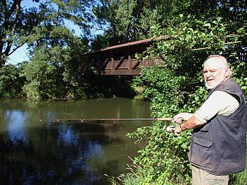 Am Schwarzacher Steg, wo der vereinigte Main ganz ruhig vor sich hinfließt, verbringt Manfred Ströhlein viele Stunden und angelt. Manchmal kommen Störche vorbei oder auch Reiher - und immer wieder erklärt Ströhlein an seinem Lieblingsplatz Touristen, dass es sich weder um den Roten noch um den Weißen Main handelt, sondern um den vereinigten. Foto: Sonny Adam