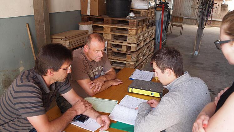 Sechs-Augen-Gespr&auml;ch: In der praktischen Abschlusspr&uuml;fung bewerten die Pr&uuml;fer (von links) Heiko Engel und Thomas Schwarzmann nicht nur Arbeiten im Umgang mit Tier und Arbeitsger&auml;ten, es wird unter anderem auch das Lesen von Dokumentationsb&uuml;chern abgefragt und sichergestellt, dass Pr&uuml;fling Henrik Gieger etwa Futtermischungen richtig berechnet. Berufsschullehrerin Tanja Schilling fiebert mit.  Foto: Katrin Huber