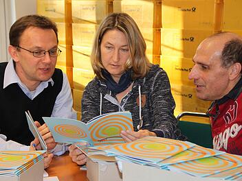 Sie haben das Heft in der Hand: Pavol Tkac (von links), Heike Kötzner und Wolfgang Reichelt vom Bayerischen Kammerorchester Bad Brückenau sortieren 7500 Broschüren mit dem Jahresprogramm 2017. Foto: Ulrike Müller