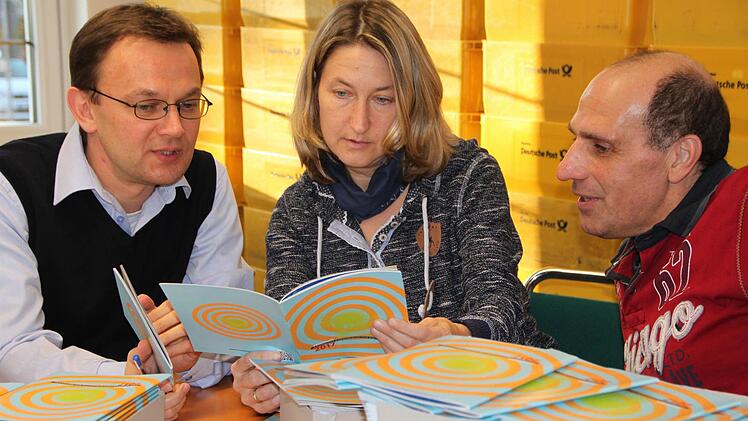 Sie haben das Heft in der Hand: Pavol Tkac (von links), Heike Kötzner und Wolfgang Reichelt vom Bayerischen Kammerorchester Bad Brückenau sortieren 7500 Broschüren mit dem Jahresprogramm 2017. Foto: Ulrike Müller