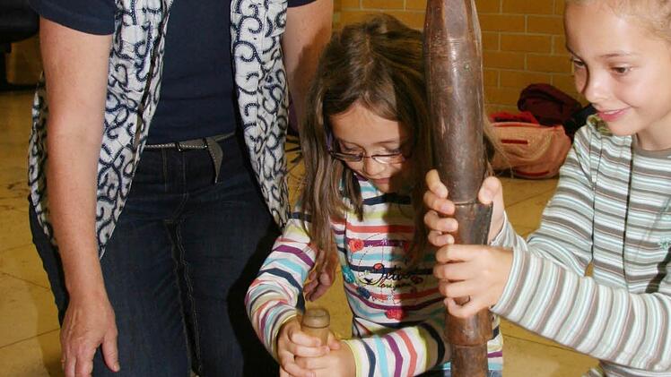 Referentin Gertrud Schweizer-Ehrler war neun Jahre Kinderkrankenschwester in Uganda und zeigt Sara Pfaffenberger (8) und Julia Goller (8), wie die Afrikaner Erdnüsse stampfen.
