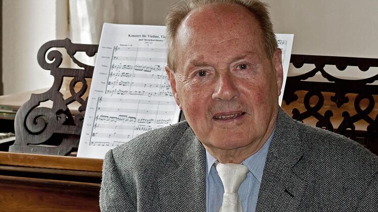 Der in Ahorn lebende Komponist Gerhard Deutschmann wird am Samstag 80 Jahre alt. Im Hintergrund: Die Partitur seines Doppelkonzerts für Violine, Violoncello und Streichorchester, das noch der Uraufführung harrt. Foto: Jochen Berger