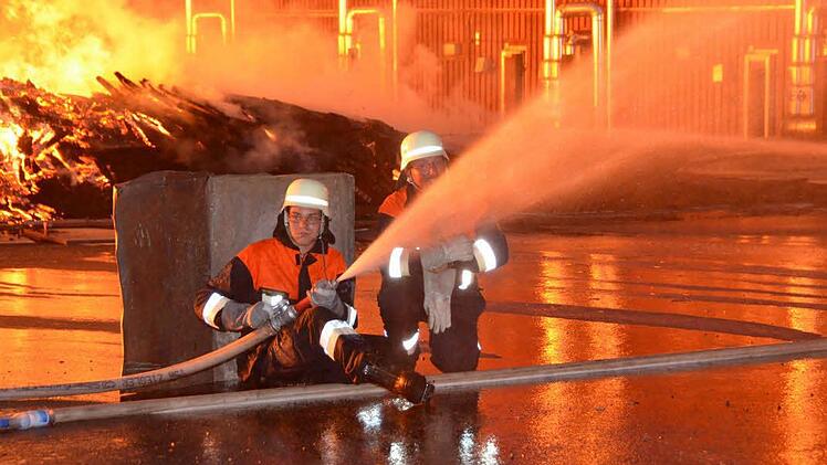 Die meterhohen Flammen waren so heiß, dass die Feuerwehrleute beim Löschen Schutz hinter Paletten und Holzstapeln suchen mussten. Foto: Rauch