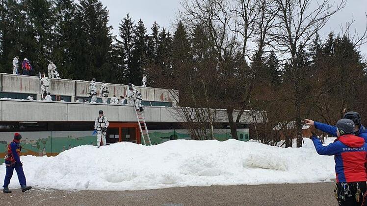 Gemeinsam mit einer Gruppe von Gebirgsjägern haben Helfer der Bergwachtbereitschaft Kulmbach-Obermain das Dach einer Schule vom Schnee befreit. Foto: Bergwacht