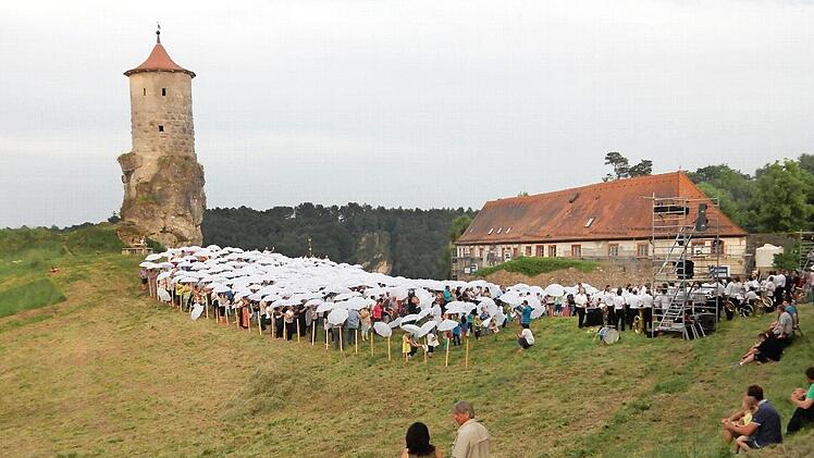 Bild mit Turm: 700 Sänger (mit weißen Regenschirmen) aus dem Gemeindegebiet singen 2015 dass neue Waischenfelder Lied anlässlich der Stadterhebungsfeiern.  Foto: Löwisch