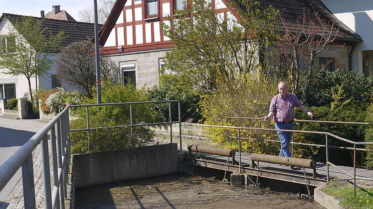 Das wird  bald alles  schöner: Bürgermeister Werner Thomas hofft, dass der Lahmer  Feuerlöschteich  nach der Neugestaltung ein bisschen einladender  als im  Moment daher kommt. Aber nicht unbedingt nur für den Biber, der  zuletzt sogar an den Balken des  Wehres unterhalb der Brücke herumgenagt hat. - Foto: Berthold Köhler