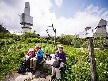 Eine Gruppe Wanderer macht auf dem Gipfel des Schneebergs vor dem ehemaligen Fernmeldeturm der Bundeswehr Rast. Foto: David Ebener/dpa