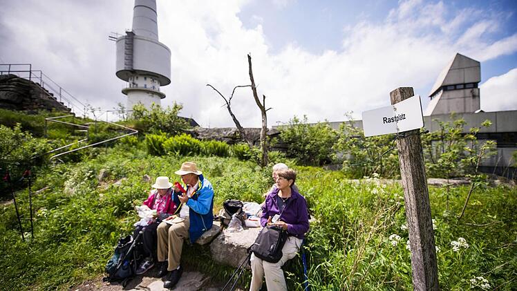 Eine Gruppe Wanderer macht auf dem Gipfel des Schneebergs vor dem ehemaligen Fernmeldeturm der Bundeswehr Rast. Foto: David Ebener/dpa
