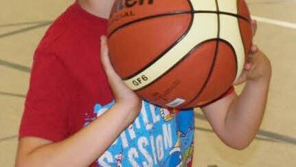 Konzentriert peilt dieser Junge den Basketballkorb an.