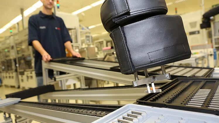 In der Bamberger Fertigung von Piezo-Aktoren - ein Produkt, das später Bestandteil eines Einspritz-Injektors wird - arbeiten inzwischen auch käfigfreie Roboter mit "Sensorhaut" Seite an Seite mit Menschen (vorne ein Greifarm eines solchen Roboters, der einen Aktor hält). Foto: Barbara Herbst