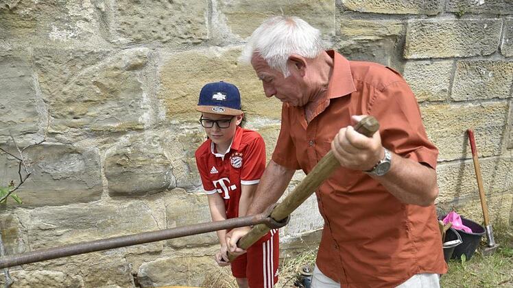 Mario Tierno und sein Opa Werner Steigmeiner probierten, einen Holzstamm für die Wasserleitung der Länge nach durchzubohren. Foto: Gerold Snater