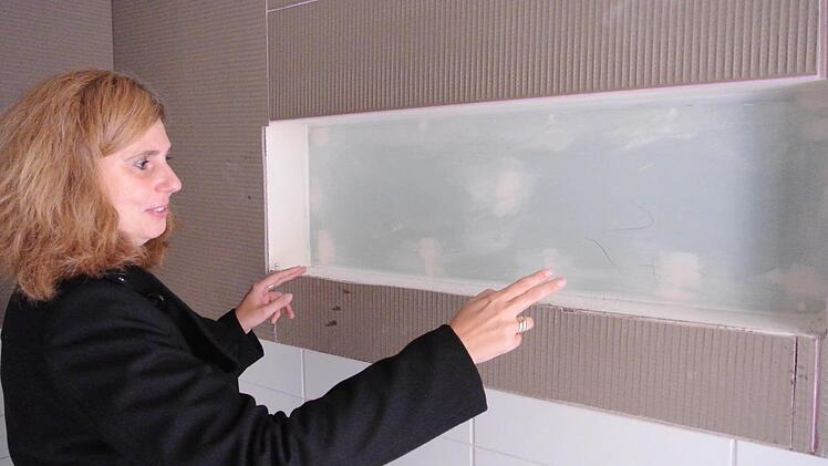 Architektin Birgit Braunschmidt zeigt, dass in jedem Bad künftig  ein Wandregal die Waschutensilien der Patienten aufnimmt,  Dem künftigen Farb- und Ausstattungskonzept für das Krankenhaus hat sie sich mit Leidenschaft gewidmet. Die neue Einrichtung wird farbig, freundlich und sehr anheimelnd.