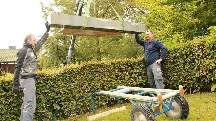 Thomas Dinkel (links) und Wolfgang Zillig von der  Staffelsteiner Steinmetzfirma Kerner setzen  einen Grabstein im Draisdorfer Friedhof, nachdem die Inschrift neu vergoldet worden ist. Foto: Matthias Einwag
