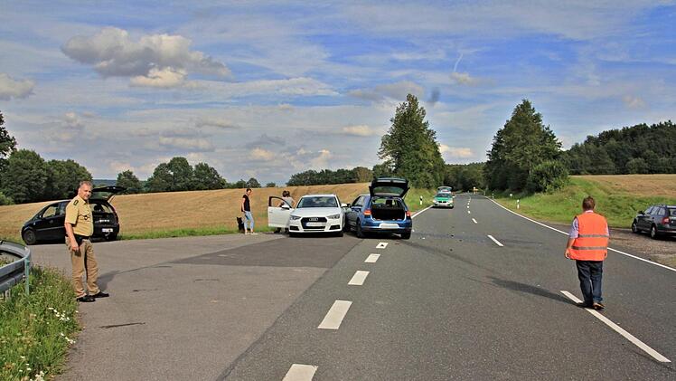 Die Unfallstelle mit den beiden Fahrzeugen in der Einmündung der Straße nach Unterpreppach (Bildmitte). Links der weiße Audi der Frau, die einbiegen wollte, rechts der blaue VW, der aufgefahren ist.