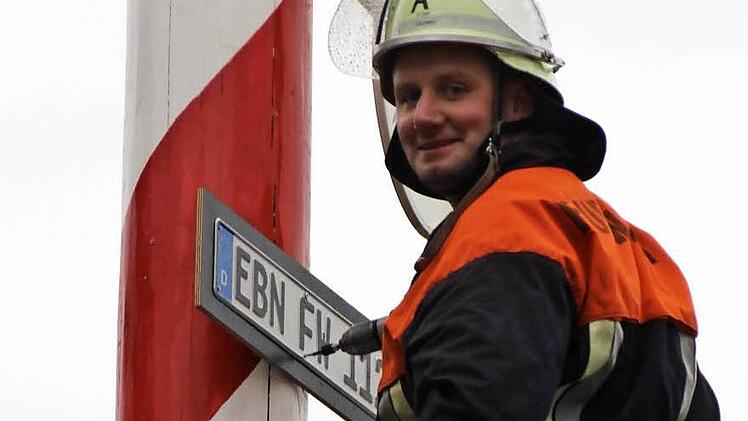 Simon Gerstenkorn befestigt das EBN-Schild in luftiger Höhe am Maibaum.  Foto: Eckehard Kiesewetter