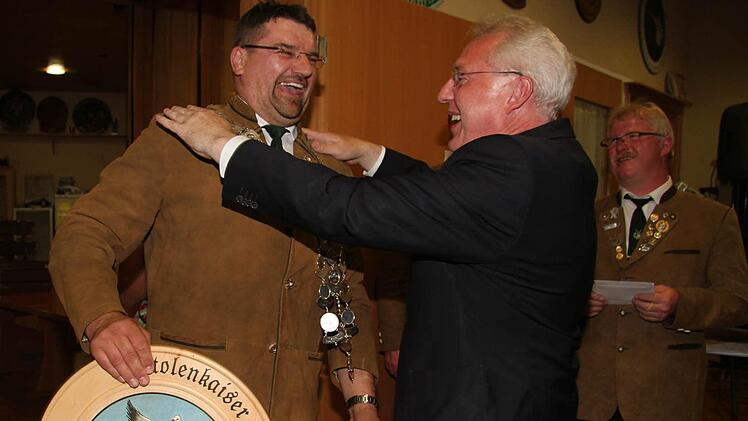 Norbert Puchtler lacht aus ganzem Herzen, als Bürgermeister Harald Hübner ihm die Königskette umhängt. Der Grund: Puchtler wurde in der Disziplin Luftpistole Schützenkaiser - und er ist der einzige Mann in einer Königinnenriege.  Foto: Adam