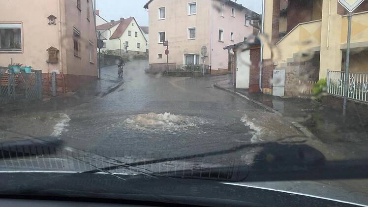 So erlebte Jacqueline Keßler das Unwetter am vergangenen Sonntag in Wollbach: Gleich mehrere Kanaldeckel in der Rhönstraße hatte es abgehoben, aus dem Kanal sprudelt das Wasser auf die Straßen. Gleich in mehreren Straßen standen Keller unter Wasser. Foto: Jacqueline Keßler