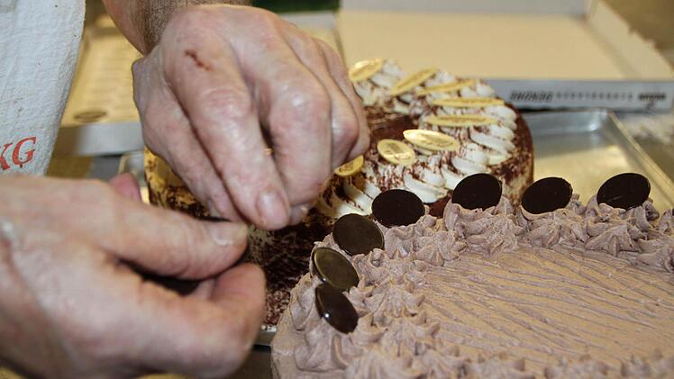 Schokoplättchen um Schokoplättchen: Ferdinand Vogler dekoriert eine seiner Schokoladentorten. Foto: Ulrike Müller