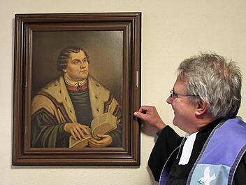 Der evangelische Pfarrer Gerd Kirchner an einem Portrait Martin Luthers, das in der Sakristei der Christuskirche im Staatsbad Brückenau hängt; Foto: Ulrike Müller