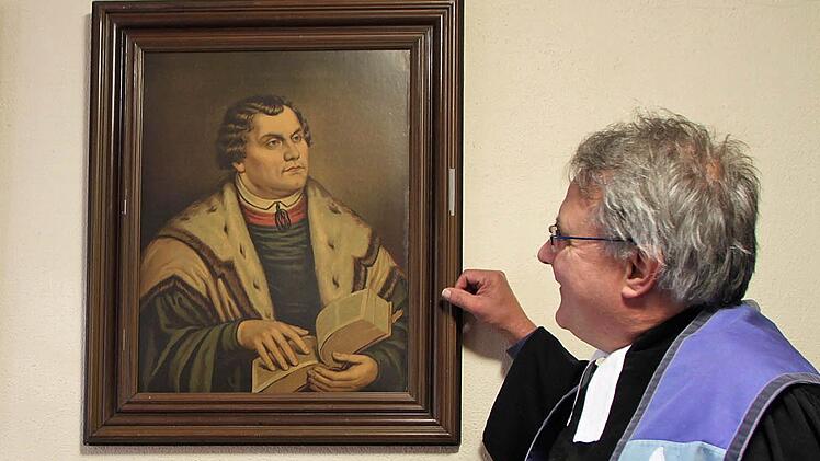 Der evangelische Pfarrer Gerd Kirchner an einem Portrait Martin Luthers, das in der Sakristei der Christuskirche im Staatsbad Brückenau hängt; Foto: Ulrike Müller