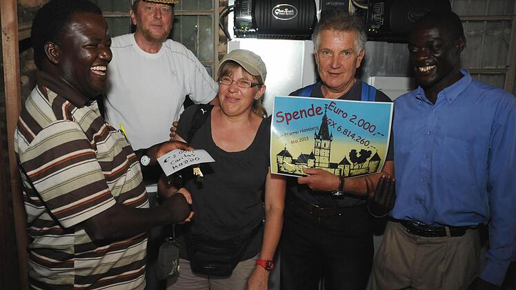 Georg Lunz, Petra Kreiner und Rudi Herbig übergeben Pfarrer Peter Ssenkaayi eine 2000-Euro-Spende für eine Solaranlage auf dem Dach der Entwicklungshilfeeinrichtung Caritas Maddo. Foto: Stefan Reinmann