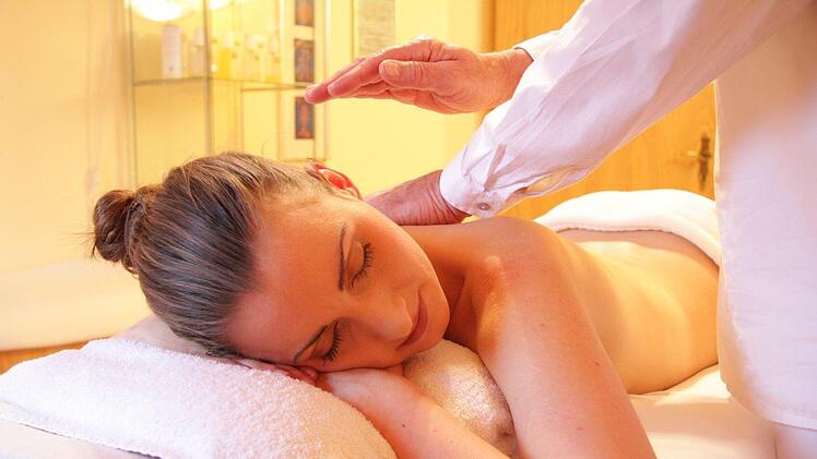 Eine Frau erhält eine entspannende Massage, liegend auf einem weißen Handtuch in einem Wellness-Bereich. Ideal für Erholung in der fränkischen Domstadt Bamberg.