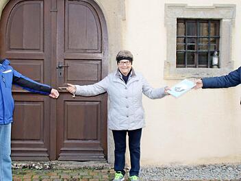 Martha Seufert erhält das Fotobuch "Sulzler Kreuzkirchle" aus den Händen von Bürgermeister August Weingart und übergibt den Schlüssel für die Kapelle an ihren Neffen Erhard Tremer.  Foto: Hilmar Ruppert