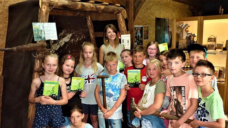 Der bergbauliche Schulunterricht mit Studentin Johanna Kestel begeisterte die Buben und Mädchen. Stolz präsentierte man im Bergbaumagazin Keilhaue und Pfannschippe (Schaufel). Im Hintergrund Stolleneingang mit Stempel und Kappe. Gerd Fleischmann