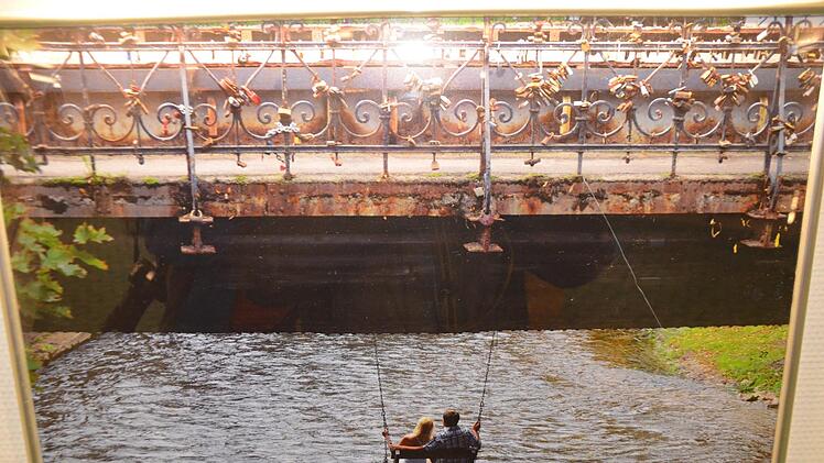 Liebespaar auf der Schaukel unter der Brücke der Liebesschlösser