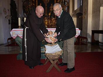 Pater Georg und Günter Metz mit dem neuen Jesuskind in der Klosterkirche am Kreuzberg.  Foto: Marion Eckert