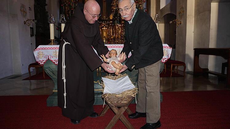 Pater Georg und Günter Metz mit dem neuen Jesuskind in der Klosterkirche am Kreuzberg.  Foto: Marion Eckert