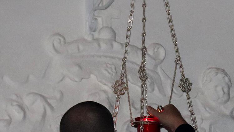 Der Mesner gibt das Ewige Licht in die Lichtampel