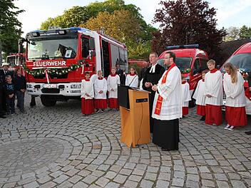Die Pfarrer Ulrich Bahr und Daniel Schuster segnen die vier neuen Feuerwehr-Einsatzfahrzeuge. Das größte ist das neue HLF der FFW Eggolsheim. Bürgermeister Claus Schwarzmann (r.) verfolgt die Weihe. Foto: Mathias Erlwein
