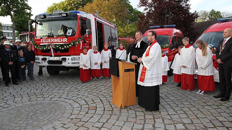 Die Pfarrer Ulrich Bahr und Daniel Schuster segnen die vier neuen Feuerwehr-Einsatzfahrzeuge. Das größte ist das neue HLF der FFW Eggolsheim. Bürgermeister Claus Schwarzmann (r.) verfolgt die Weihe. Foto: Mathias Erlwein
