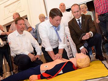 Unter fachkundiger Leitung "reanimiert" hier MdL Sandro Kirchner eine Übungspuppe. Ihm stehen Rotkreuz-Ausbilder Thomas Menz (links) und BRK-Kreisvorsitzender Bad Kissingen, Dr. Alexander Siebel (rechts) zur Seite. Foto: Peter Rauch