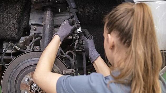 Eine Kfz-Mechanikerin wechselt in einer Werkstatt die Bremsscheibe eines Autos. Marijan Murat, dpa