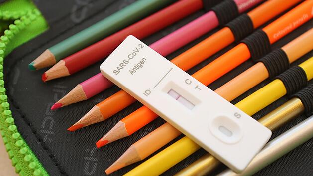 Ein Corona-Testkit liegt im Klassenzimmer zum Unterrichtsbeginn auf einer Federtasche. Sp&auml;testens jeden zweiten Tag wird in den Schulen getestet. Doch seit Januar h&auml;ufen sich die Falschmeldungen.