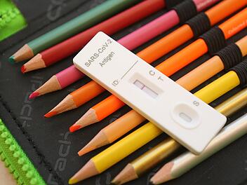 Ein Corona-Testkit liegt im Klassenzimmer zum Unterrichtsbeginn auf einer Federtasche. Spätestens jeden zweiten Tag wird in den Schulen getestet. Doch seit Januar häufen sich die Falschmeldungen.