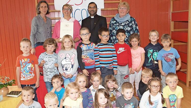 Kindergartenleiterin Erika Felix (links), Pfarrer George Thottankara (Zweiter von rechts) und die Kindergartenbeauftragte der Kirchenstiftung, Hedwig Träger (rechts), sowie ein Teil der 75 Kindergartenkinder gratulierten Nicole Wagner (Zweite von links) zu ihrem Dienstjubiläum. Foto: Alfred Thieret