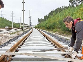 Die Bahnmitarbeiter Peter Albertz (links) und Valerie Bonda winkeln bei Wolfsberg (Thüringen) Schienen am künftigen Überholbahnhof Ilmenau-Wolfsberg der ICE-Neubaustrecke Ebensfeld-Erfurt aus. Foto: Michael Reichel/dpa