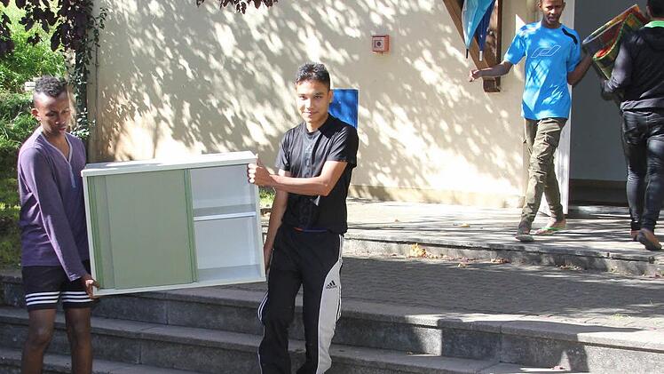 Hassan, Hamid, Sakariye und Faisal helfen beim Ausladen der Schränke und Teppiche, als das Heim im Oktober 2015 dank einer Spende aufmöbliert wurde.