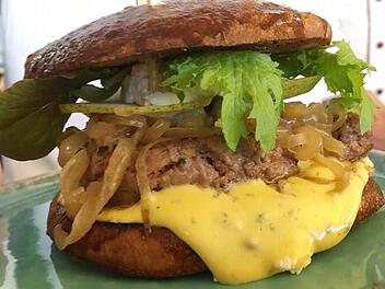 Der siegreiche Oberfrankenburger wurde von Matthias Sprenger und Benedikt Kraus vom Landgasthof Detsch in Haig (Landkreis Kronach) entwickelt. Das Patty besteht aus Fleisch vom Anguskalb und Speck vom Mangalitza-Strohschwein, beides aus der Region, gewürzt mit Salz und Pfeffer. Das Brötchen ist ein Treber-Brioche auf Sauerteigbasis mit heimischen Zutaten. Zum perfekten Burger gehören natürlich heimische Zwiebeln, die in diesem Fall mit einem Pale Ale einer Brauerei aus der Region veredelt wur...