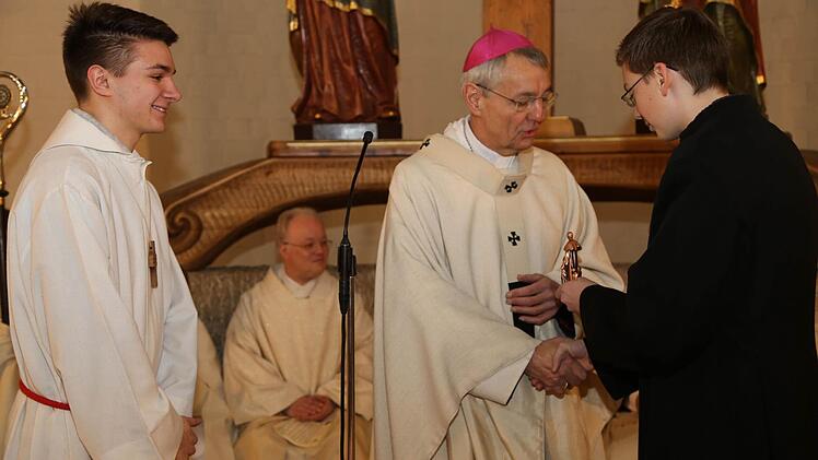 Simon Herden und Julian Lüttich übergeben Erzbischof Ludwig Schick eine kleine Figur von Don Bosco.