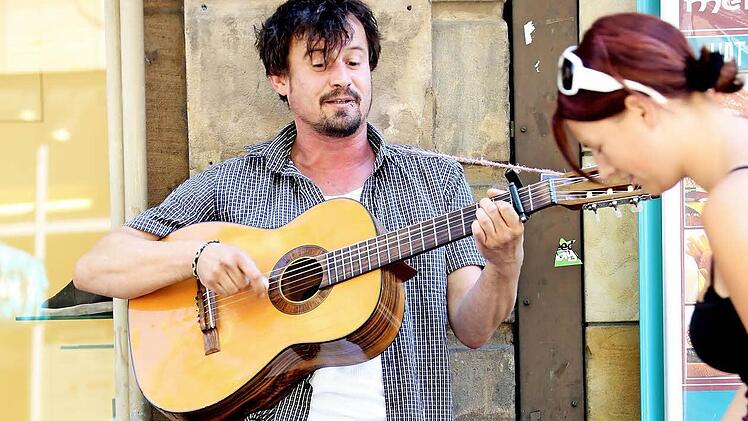 So kennt man den Straßenmusiker in Bamberg, singend mit Gitarre.