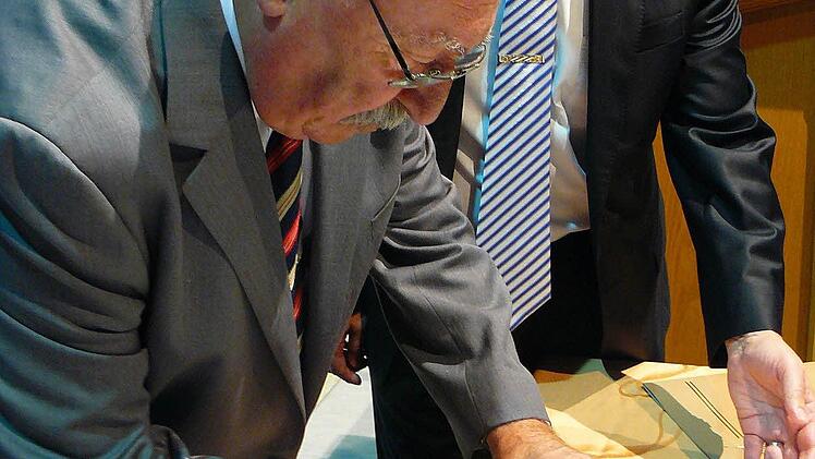 Gabor Penzes (vorne) unterzeichnet den Ehrenbrief des Marktes Marktleugast.