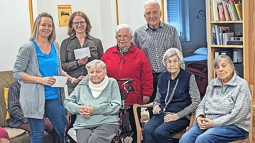 Norbert Lawatsch (hinten, r.), Elisabeth Ramming (Strickkreis, links daneben) Diana Pausch (Sozialstation, links daneben), Eva Seibold (Tagespflege, links daneben) sowie im Vordergrund G&auml;ste der Tagespflege bei der Spenden&uuml;bergabe.