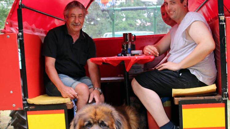 Gut, wenn man zum Bulldog den passenden Planwagen gebaut hat: Beim Regen hatten Ulrich Kalb, Melanie Döring und Jörg Kalb aus Weitramsdorf (von links) gut lachen. Selbst Hund Ben fand im Anhänger Platz. Foto: Bettina Knauth