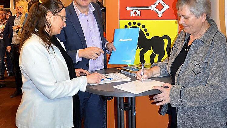 Bürgermeister Karl-Heinz Wagner und seine Stellvertreterin Barbara Zeh (rechts im Bild) gingen mit gutem Beispiel voran und unterschrieben noch am Abend die zwei notwendigen Verträge. Der eine ist ein Grundstücksnutzungsvertrag, der der Gemeinde den Zugang zum Grundstück für die Verlegung des Mikrorohres für das Kabel und den Zugang für die Hausverkabelung erlaubt. Dazu kommt noch der Vertrag mit dem BürgerNet. Dieser wird dann entsprechend den Anforderungen der Bürger gestaltet. Foto: Andrea...